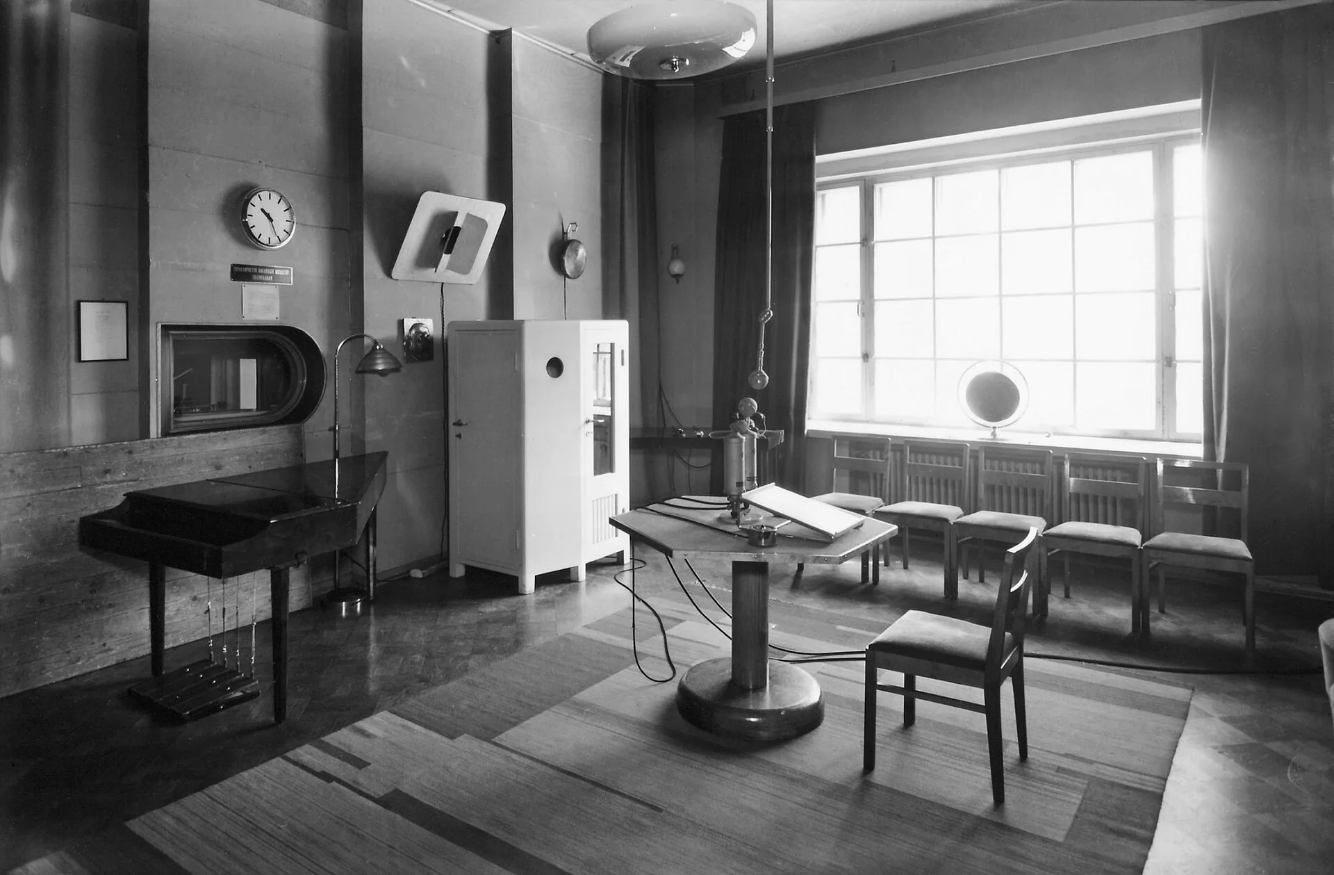 Studio 3 of the Broadcasting House on Fabianinkatu street in Helsinki. A radio drama studio during the war. In the center, a hexagonal microphone table. Estimated date of photography is precise to the year.