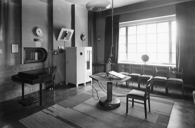 Studio 3 of the Broadcasting House on Fabianinkatu street in Helsinki. A radio drama studio during the war. In the center, a hexagonal microphone table. Estimated date of photography is precise to the year. Radio advertising measurement explained for UK media buyers