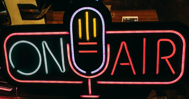 Bright neon 'On Air' sign glowing in a dark studio, perfect for broadcasting themes. What radio advertising return on investment means for England media buyers